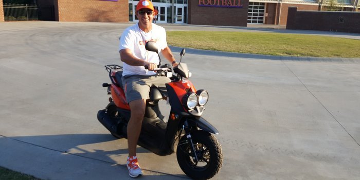 Swinney sits on a moped he occasionally rides around campus - but with a helmet 